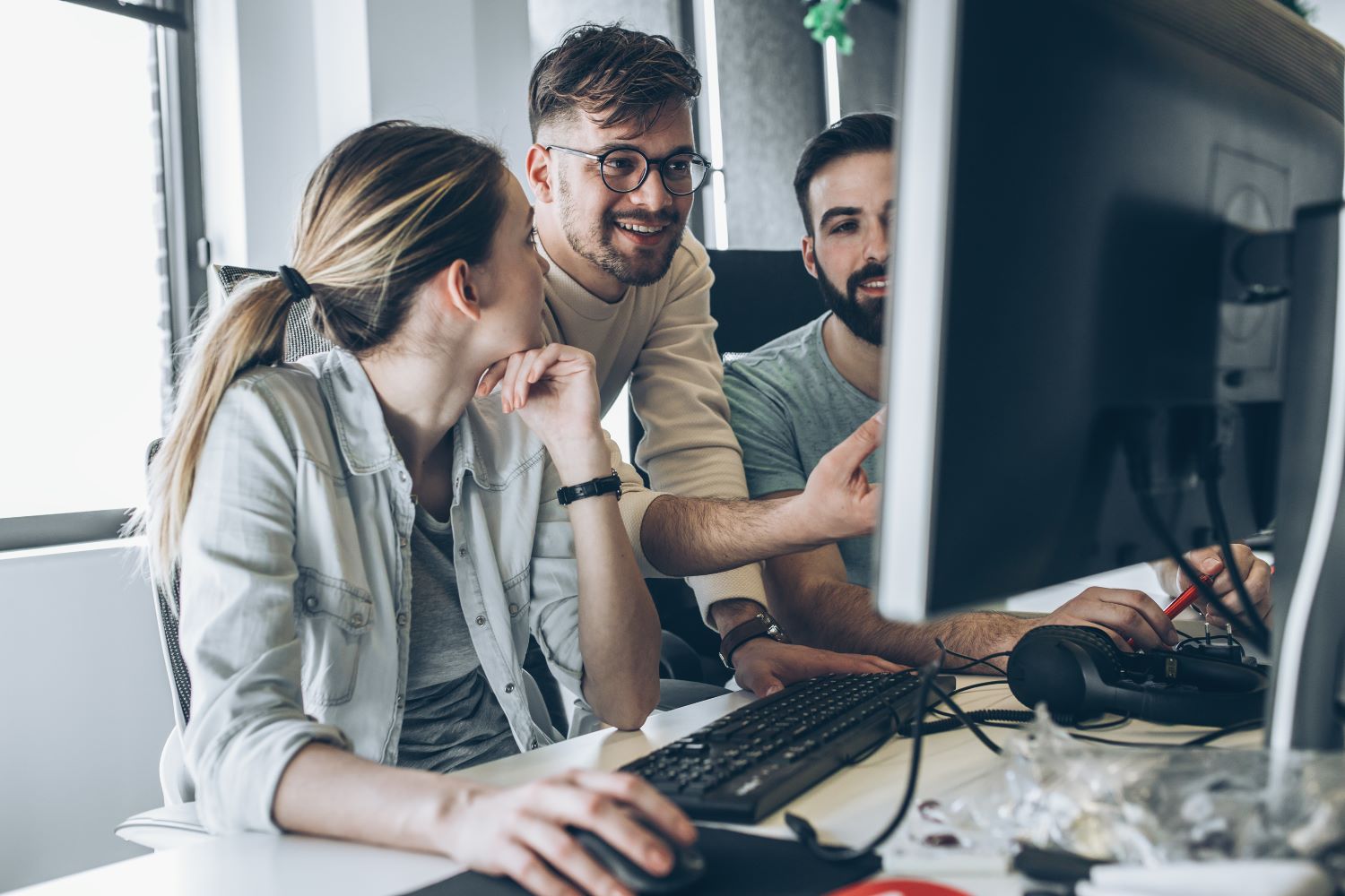 3 mensen die kijken naar een computerscherm en overleggen wat er te zien is.