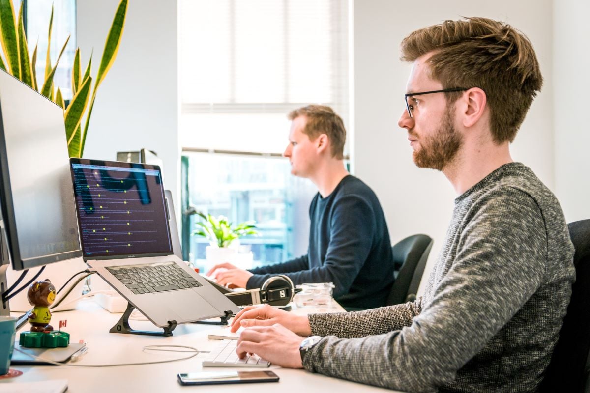 Twee mannen aan het werk in de ICT kijkend naar de cijfers op het computerscherm.