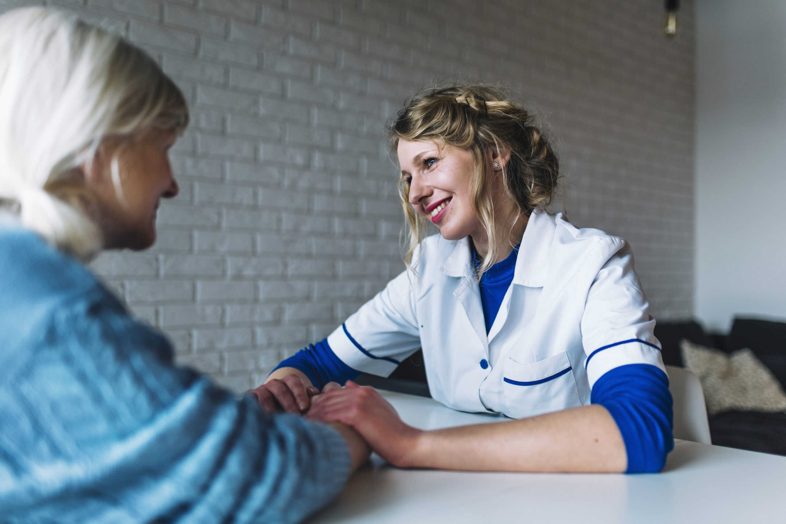 een persoonlijk begeleider die een oudere vrouw toespreekt en haar helpt