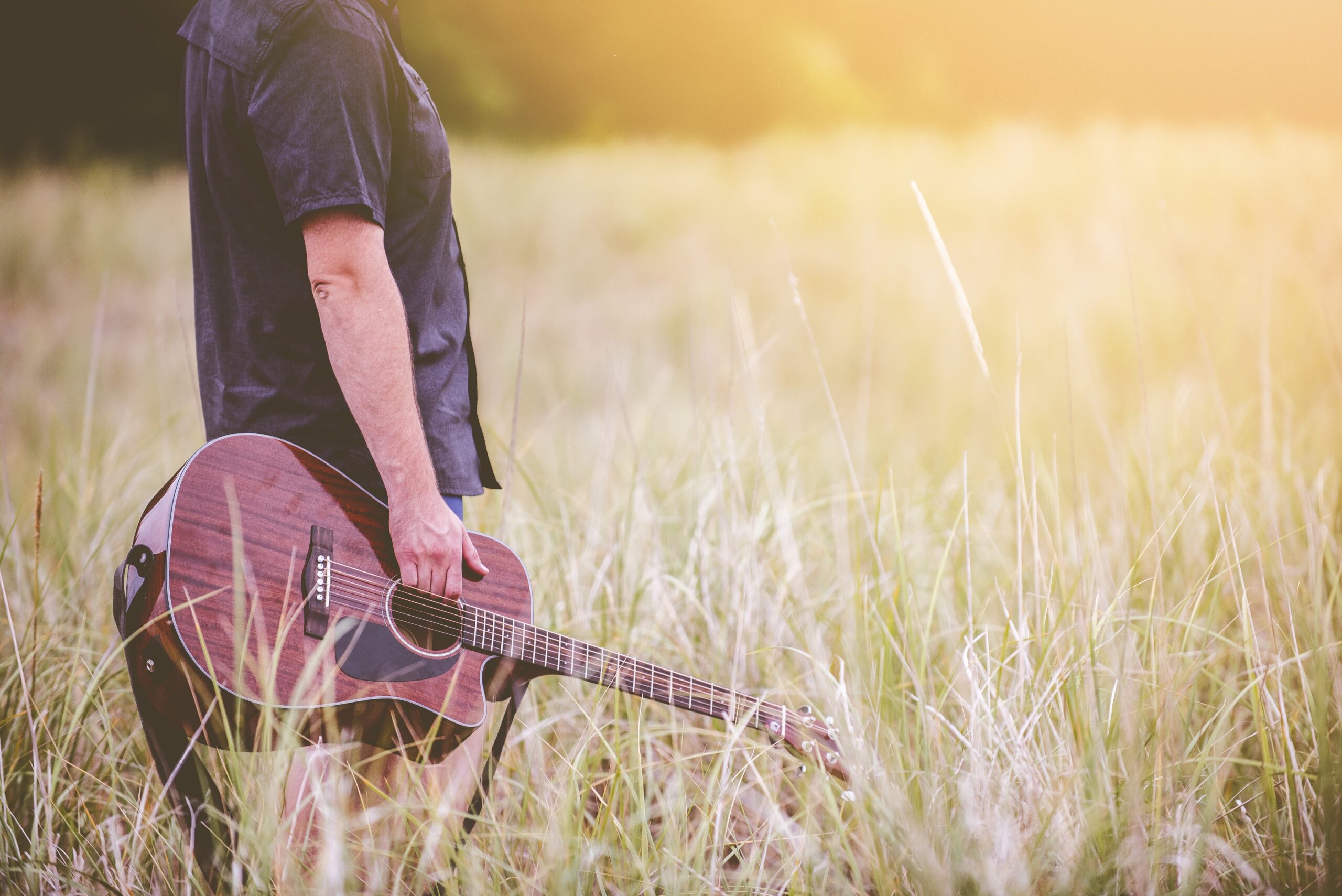 man met gitaar in de velden